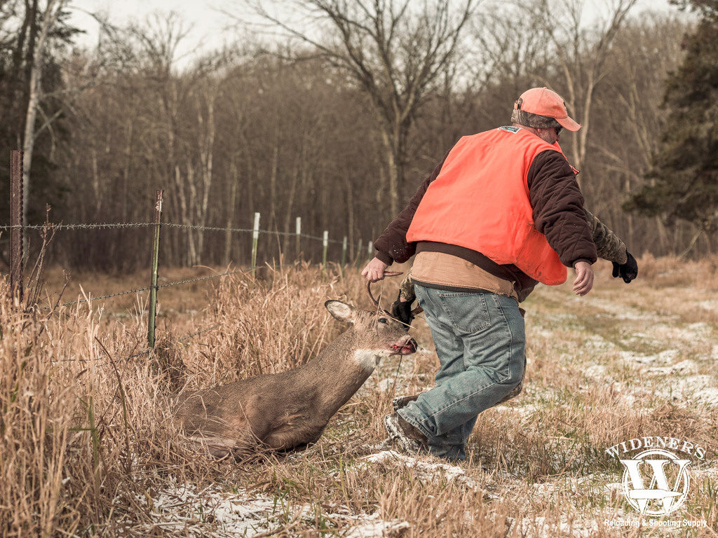 a photo of hunters dragging a deer