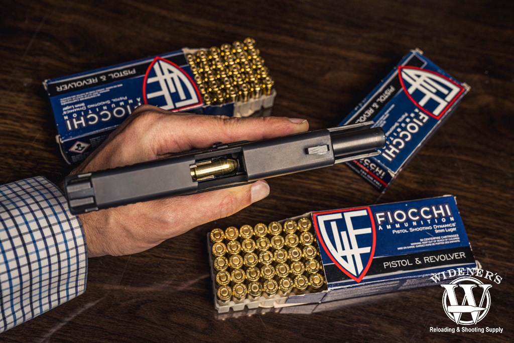 a man holding a 9mm pistol next to fiocchi ammo a photo of a man holding a 9mm pistol next to fiocchi ammo