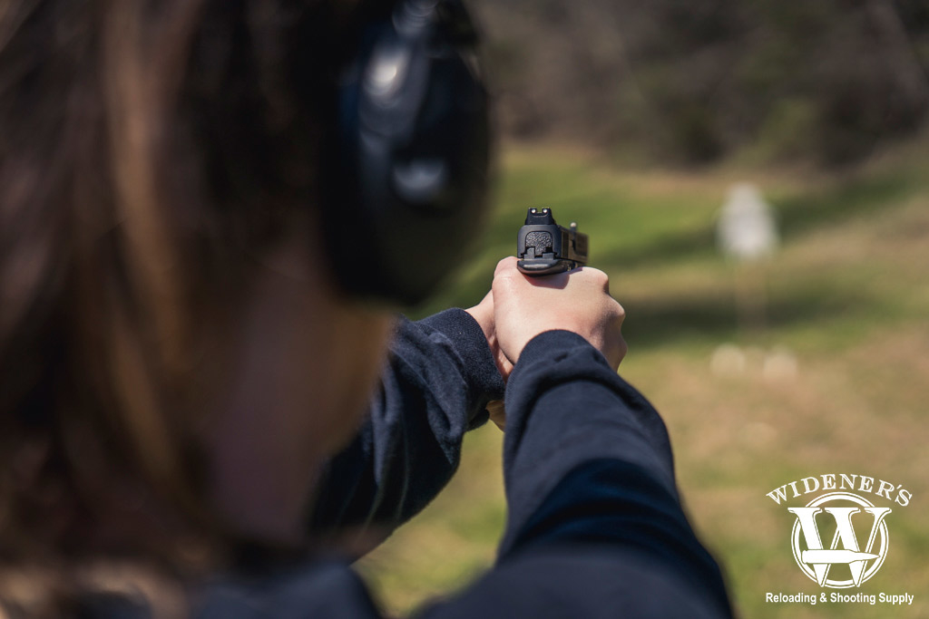 female competition shooter firing at a steel target photo of a female competition shooter firing at a steel target outdoors