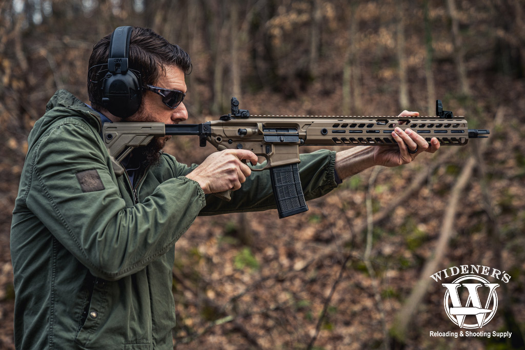 a photo of a man shooting a rifle in the woods