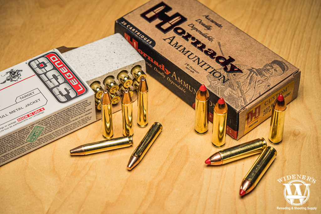 350 legend ammo next to 450 bushmaster ammo A photo of 350 legend ammo next to 450 bushmaster ammo on a sheet of plywood.