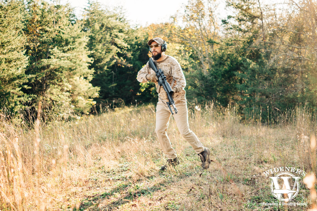 a photo of a man outdoors with a recce rifle