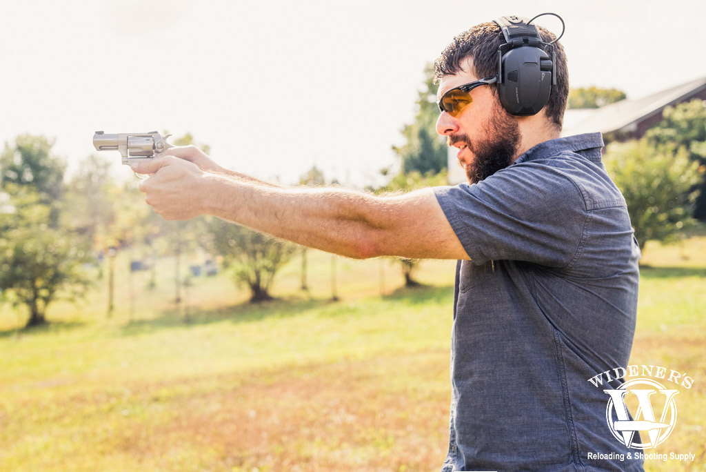 a man shooting a revolver outdoors a photo of a man shooting a revolver outdoors