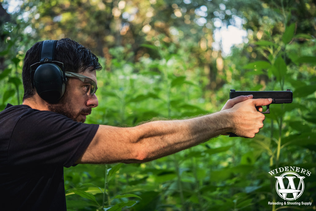 man shooting a glock pistol outdoors a photo of a man shooting a glock pistol outdoors