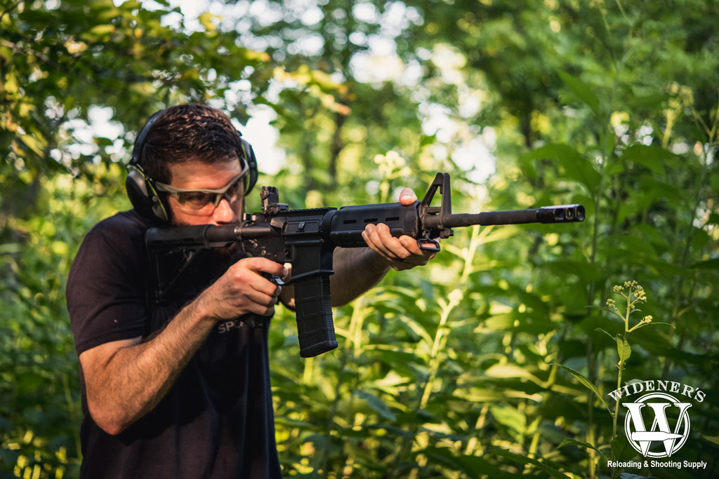 a photo of a man shooting an ar-15 rifle outdoors