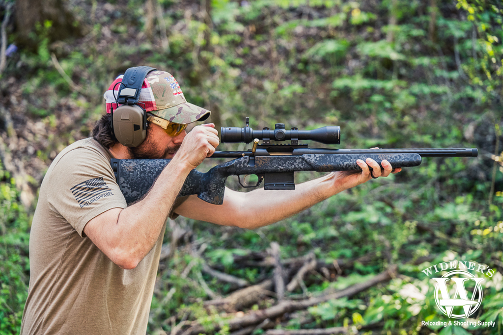 a photo of a man shooting a bolt action rifle