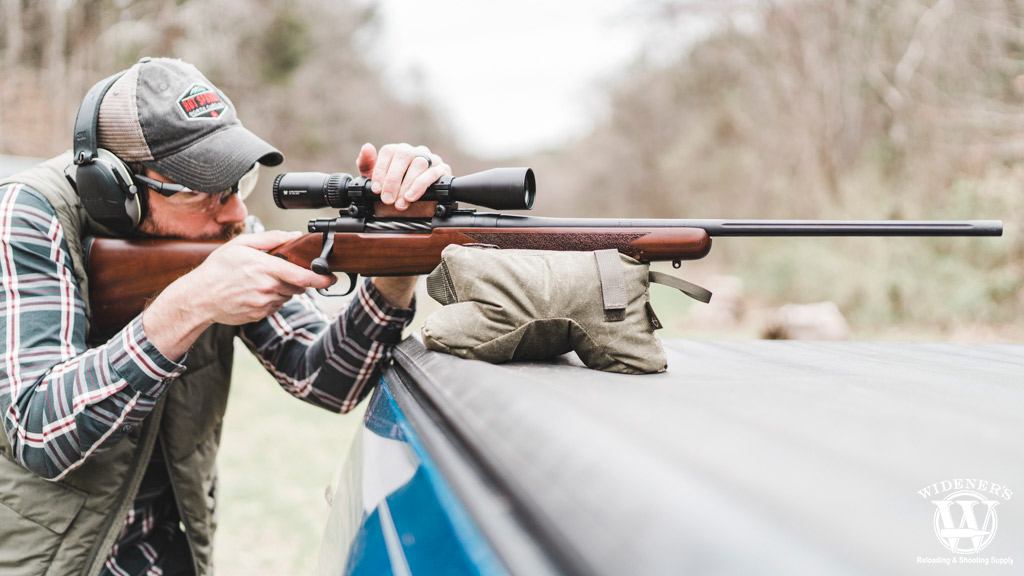 a photo of a man shooting a bolt action rifle