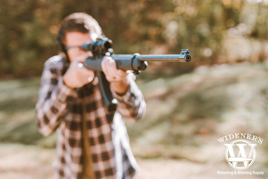 a photo of a man shooting a rimfire rifle outdoors