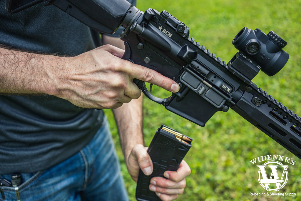 reloading an ar-15 rifle outdoors a man reloading an ar-15 rifle outdoors