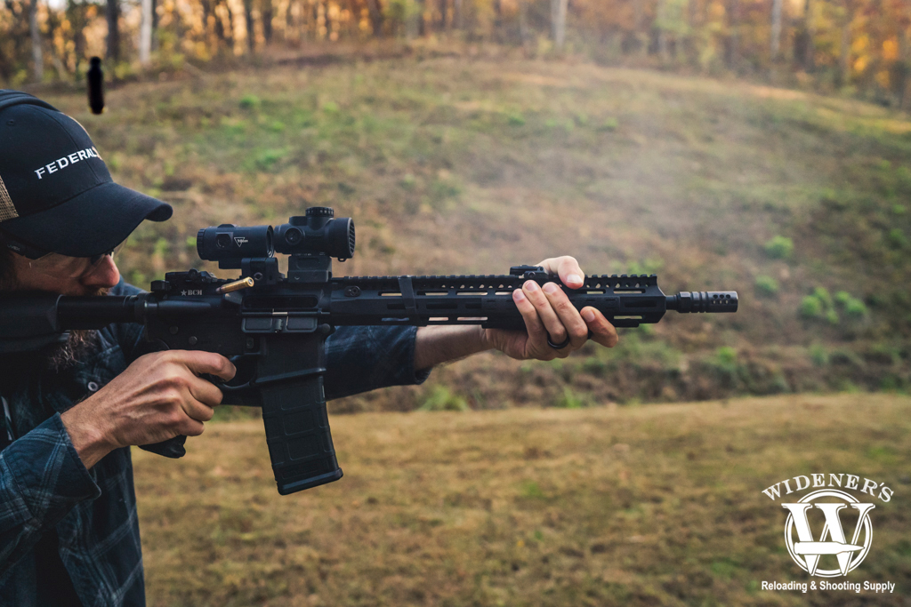 a photo of a man shooting an ar-15 rifle outdoors