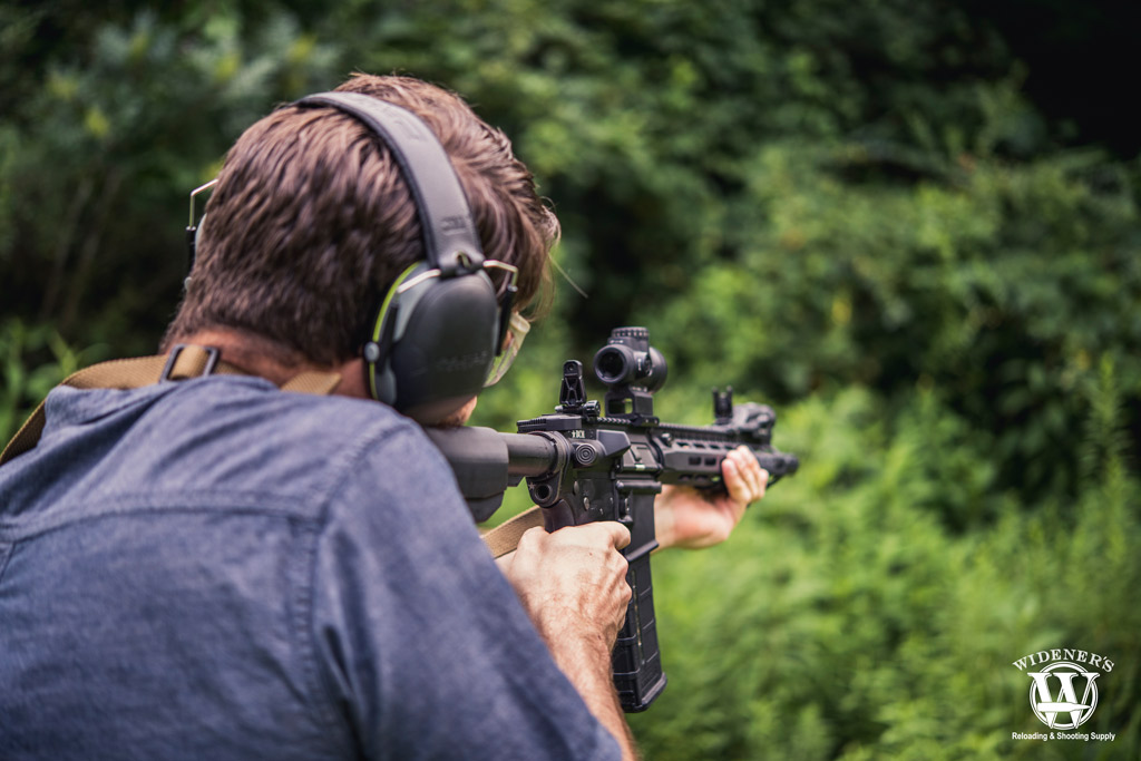 a photo of a man shooting an ar-15 rifle outdoors