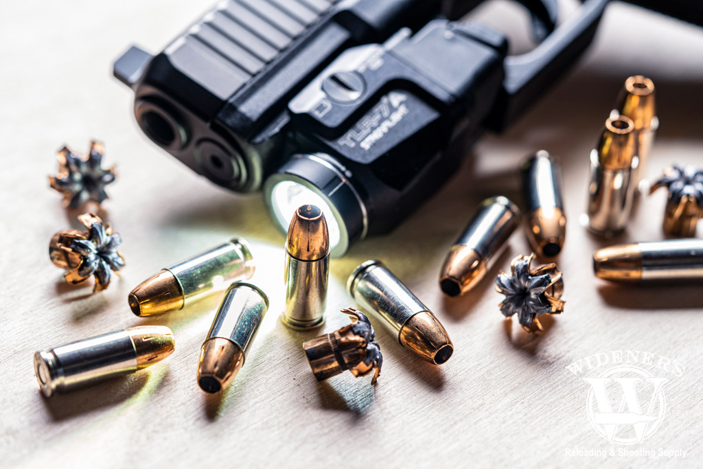 a photo of a handgun with a flashlight attachment surrounded by ammo
