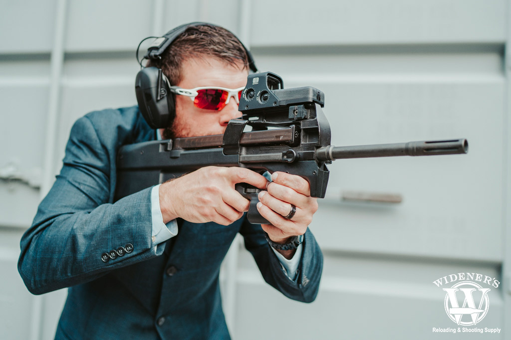 sharp dressed man shooting an fn ps90 gun a photo of a sharp dressed man shooting an fn ps90 gun