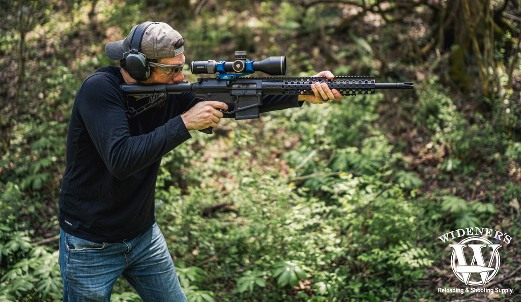 a photo of a man shooting a rifle in the woods