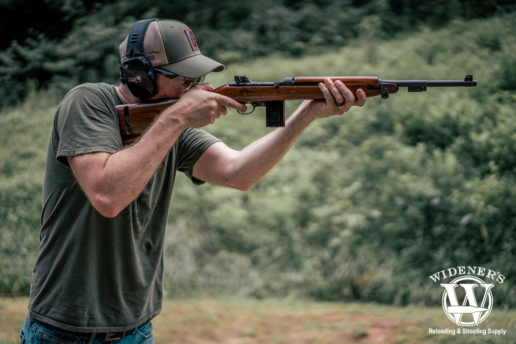 a photo of a man shooting an m1 carbine rifle outdoors