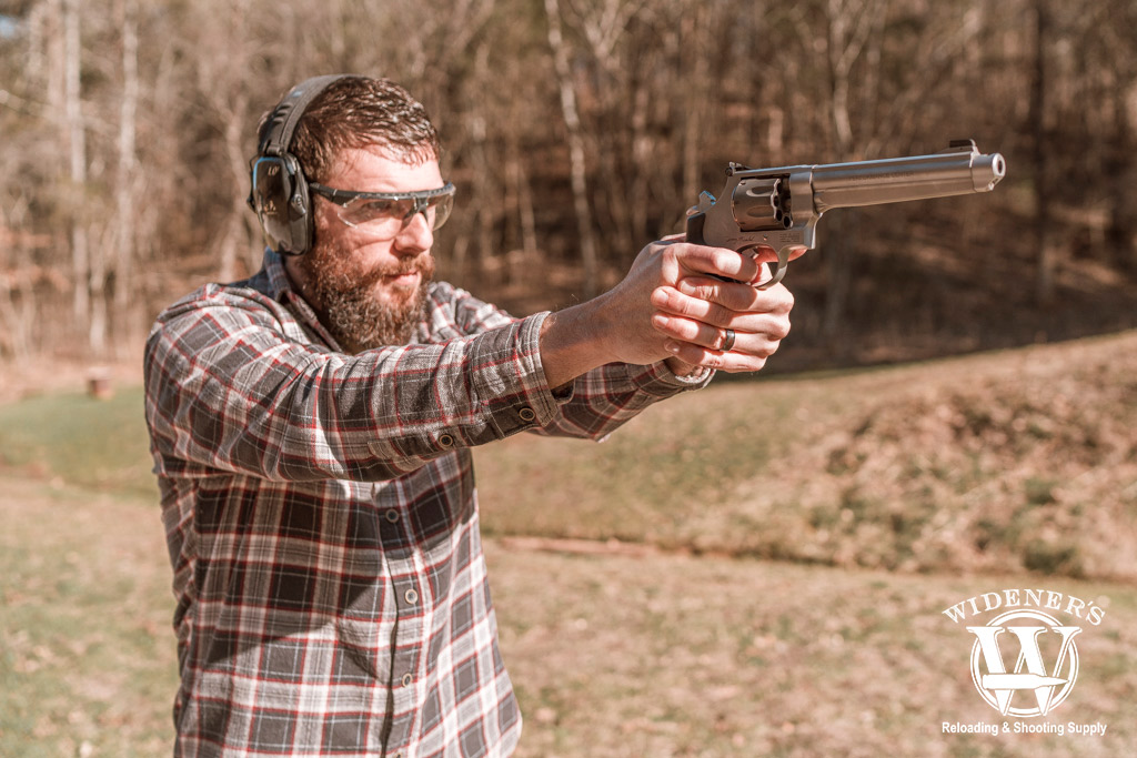 a man shooting a double action revolver outdoors a photo of a man shooting a double action revolver outdoors