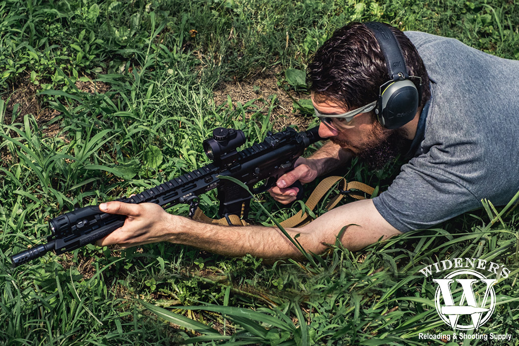 a photo of a man shooting an ar-15 rifle outdoors