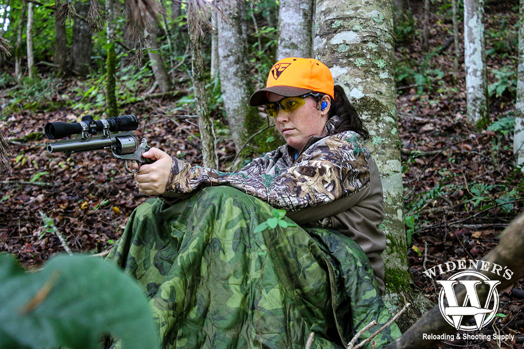 a photo of a female handgun hunting in the woods