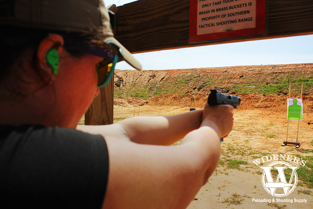 female shooting a gun with iron sights at an outdoor range a photo of a female shooting a gun with iron sights at an outdoor range
