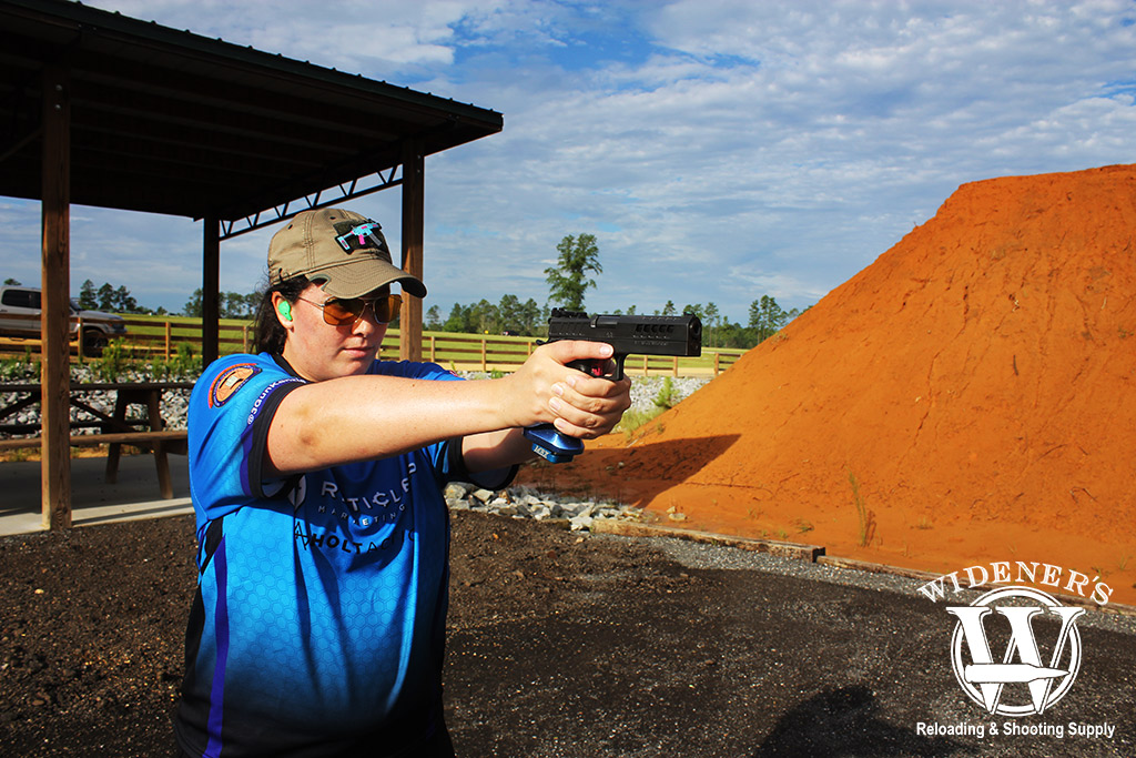 female shooter shooting a pistol at an outdoor gun range a photo of a female shooter shooting a pistol at an outdoor gun range