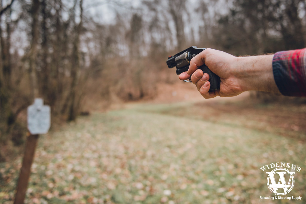 a photo of a man shooting a revolver outdoors