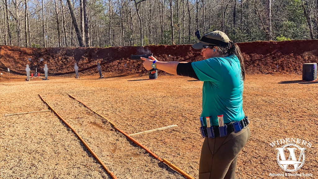 a female shooting a competition pistol outdoors a photo of a female shooting a competition pistol outdoors