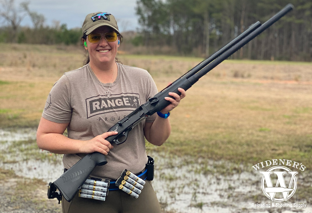 a photo of a female competition shooter holding a shotgun